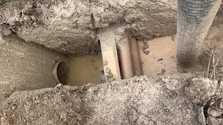 Underground utilities exposed in muddy excavation pit Sydney
