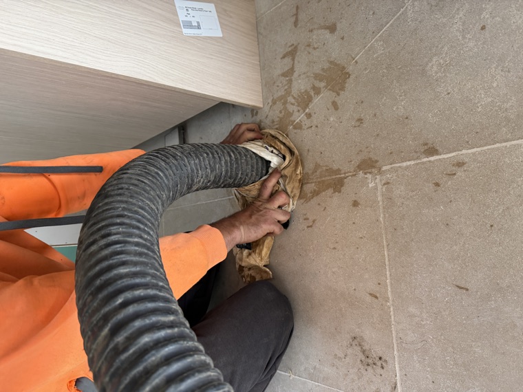 Worker with vac hose indoor tight access excavation Sydney