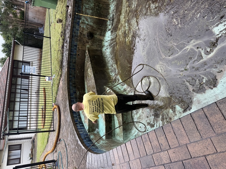 Worker removing pool sludge with vac truck hose Sydney
