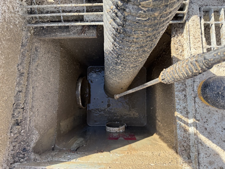 Vac truck hose removing sludge from sewer pit through grate Sydney